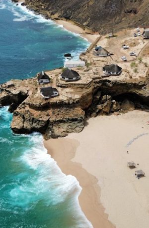 Coastal village with thatched roof huts on cliffs overlooking cliffs.